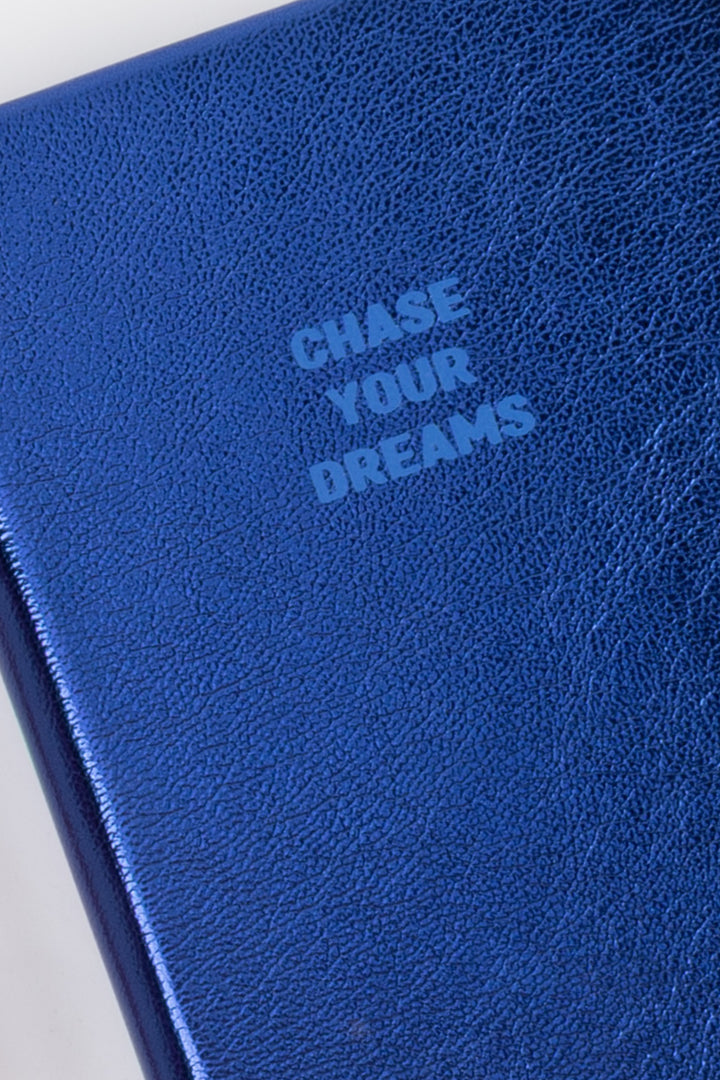 Close-up of the A6 metallic blue notebook cover showing the Chase Your Dreams text in matching blue
