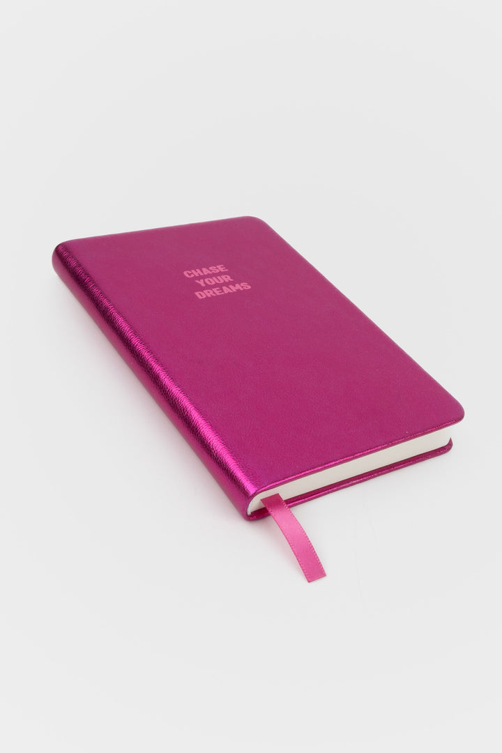 Angled view of closed pink metallic A6 notebook with pink ribbon marker
