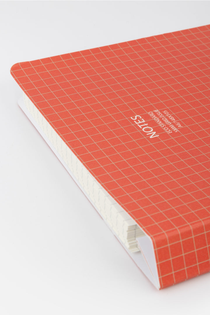 Notebook with red grid cover and white text on a white background