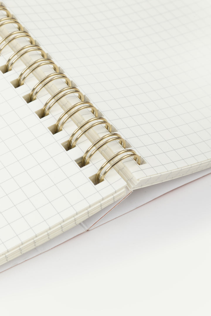 Close-up of a notebook with a grid pattern on a white background