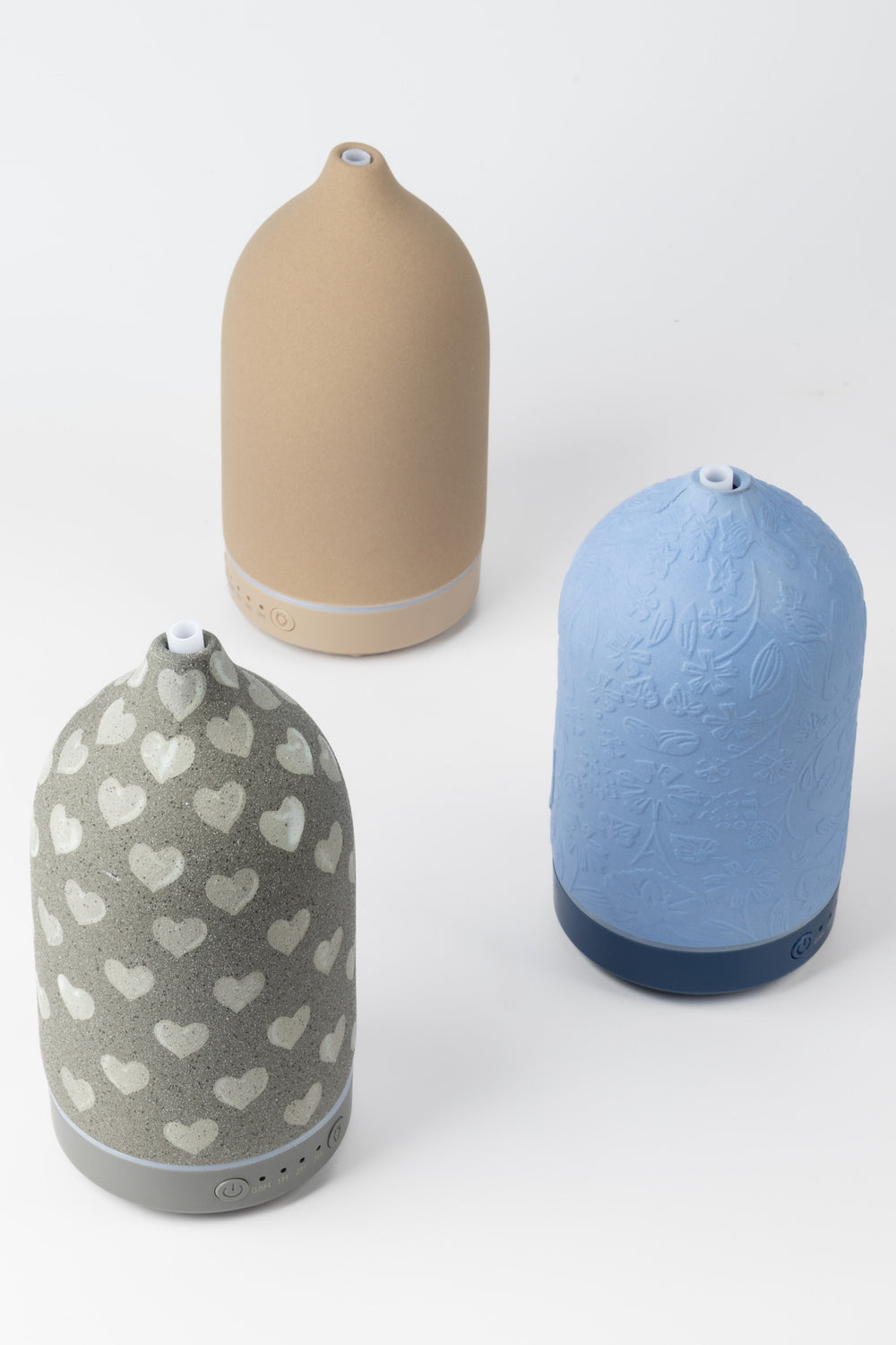 Three diffusers in beige, gray with heart pattern, and blue on a white background