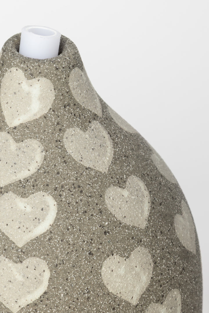 Decorative diffuser with heart patterns on a plain background