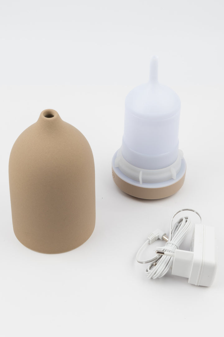 Brown ceramic vase, white diffuser, and white plug on a light gray background
