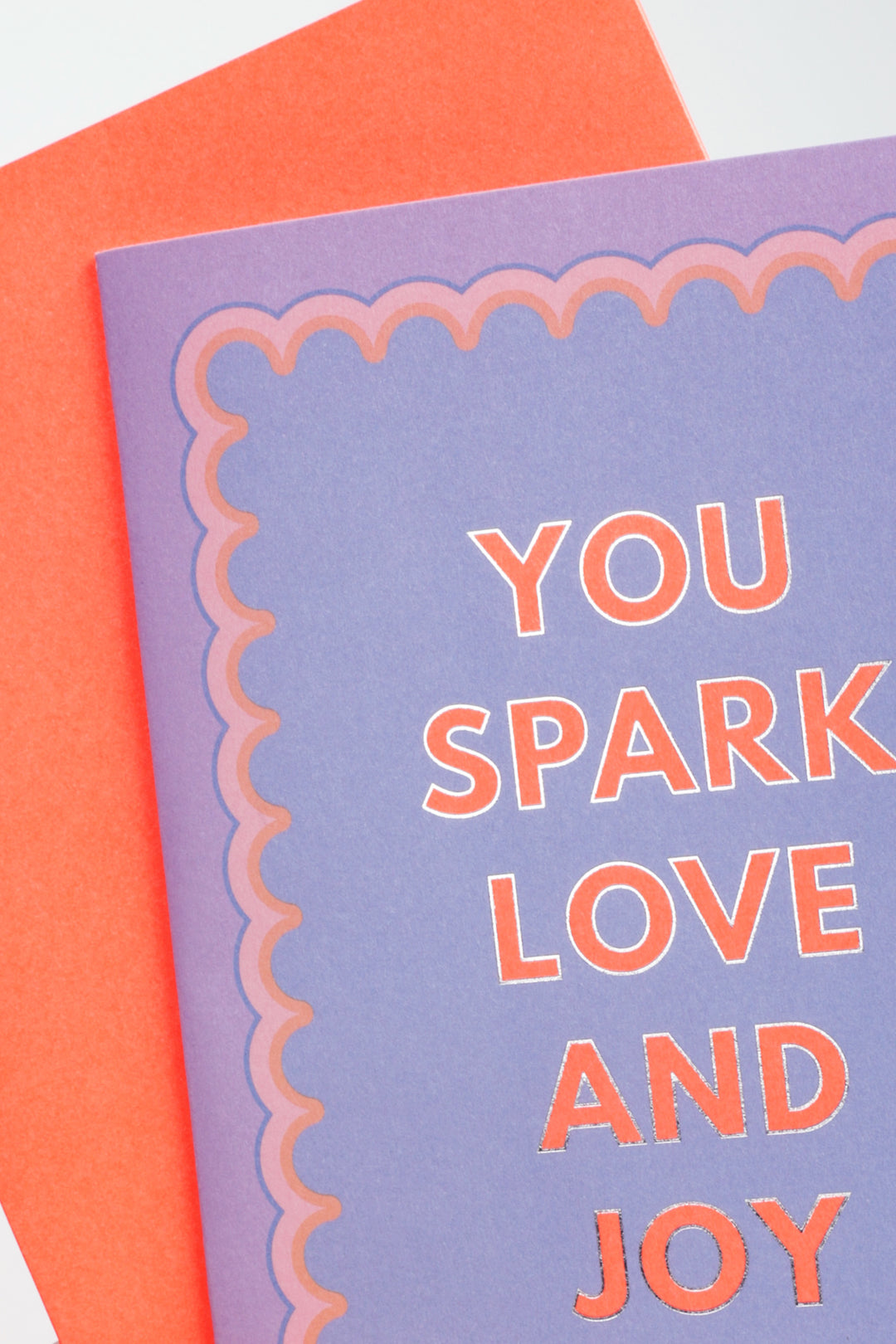 Purple card with orange text 'YOU SPARK LOVE AND JOY' on an orange envelope