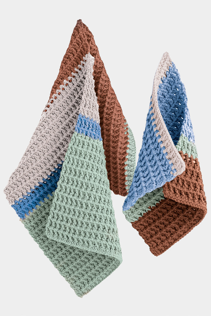 Three crocheted guest towels with gradient colors on a white background