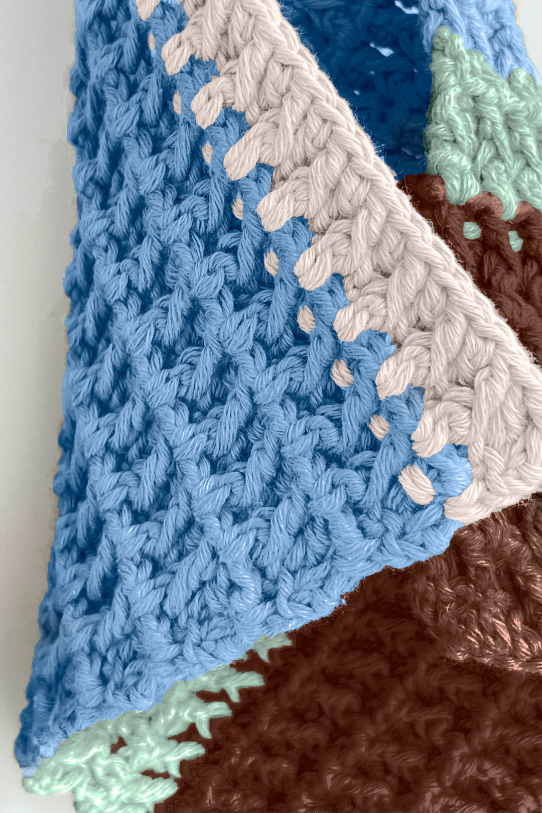 Close-up of a crocheted towel with blue, brown, and green colors.
