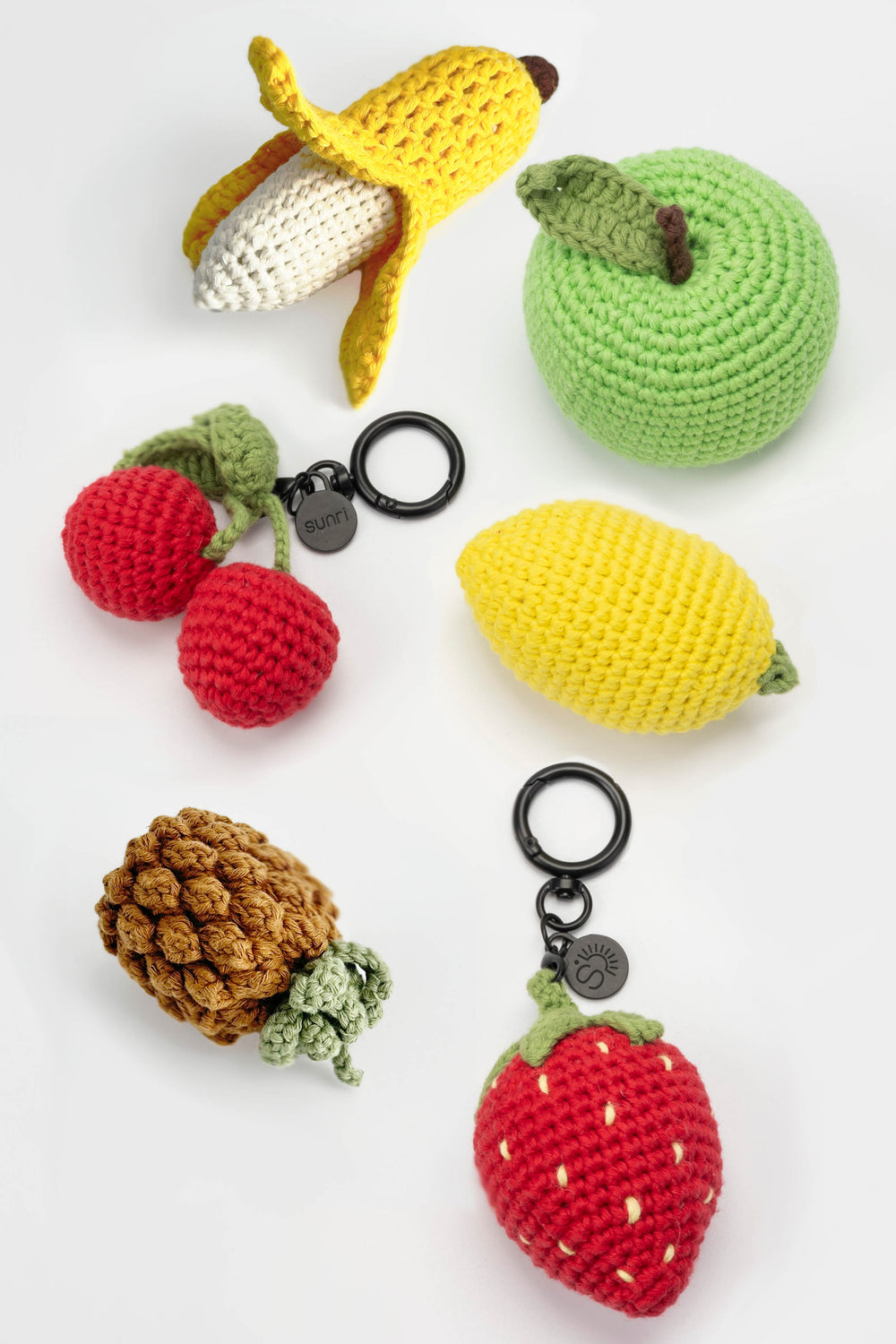 Collection of crocheted fruit keychains on a white background