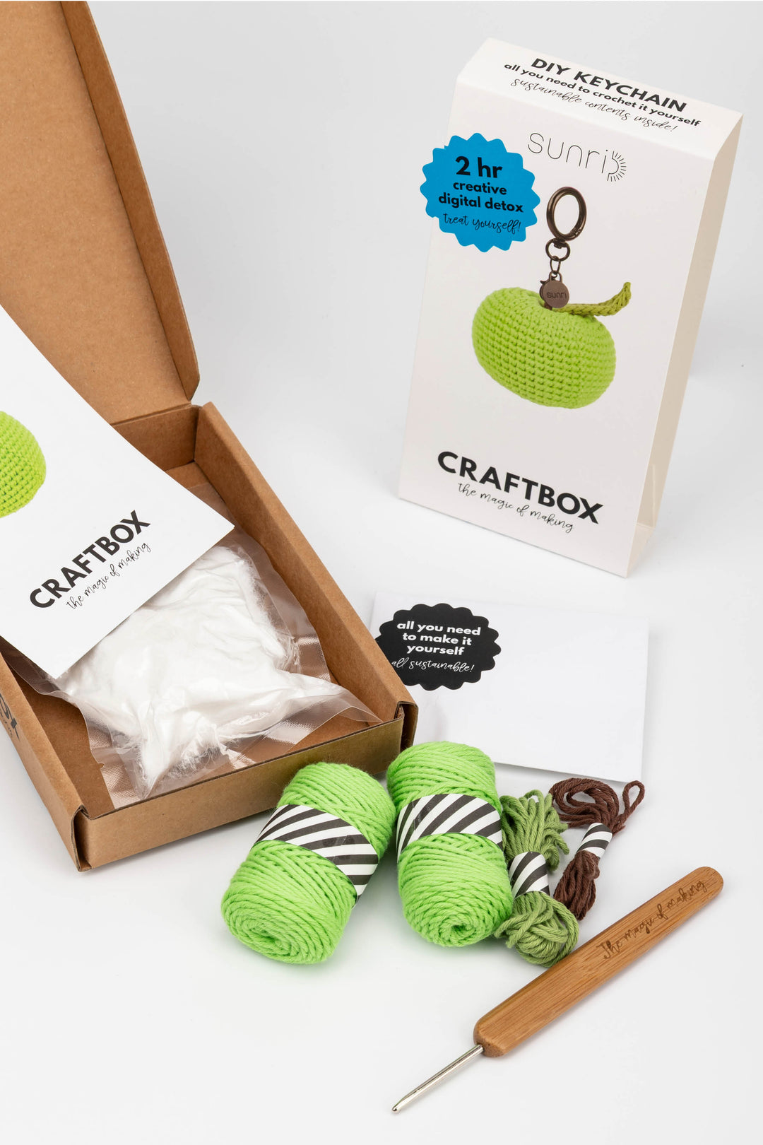 Craft kit with yarn, crochet hook, and keychain in a box on a white background