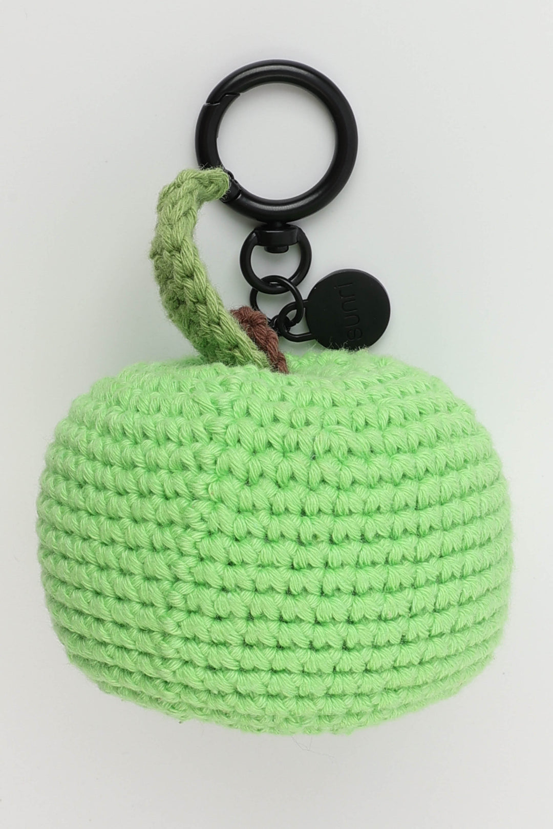 Green crocheted apple keychain on a white background