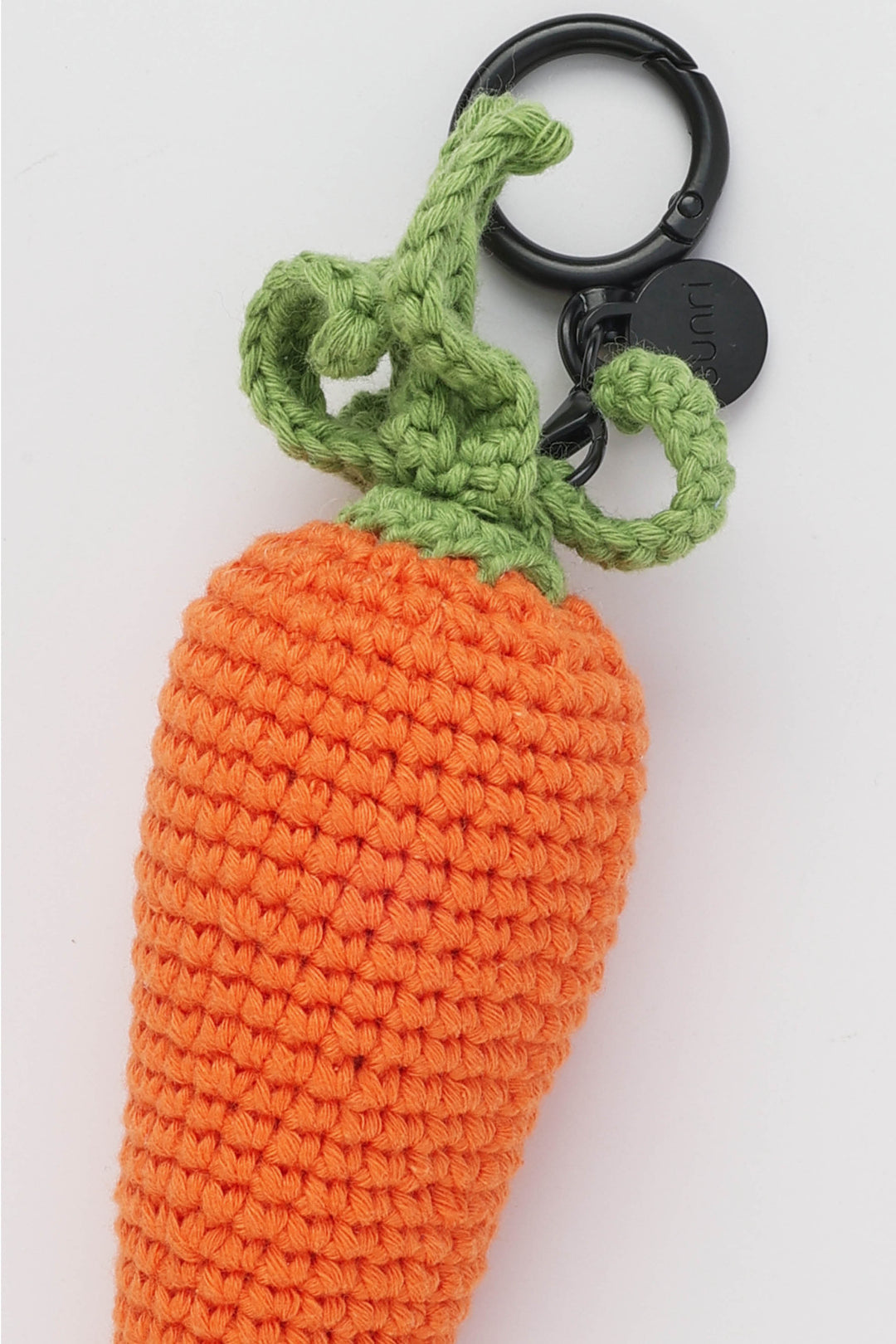 Crocheted carrot-shaped keychain with a black ring on a white background