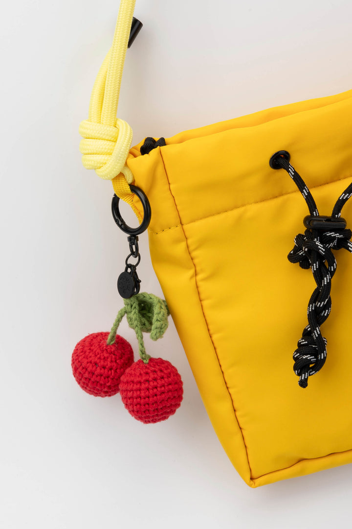 Yellow pouch with a crochet cherry keychain on a white background