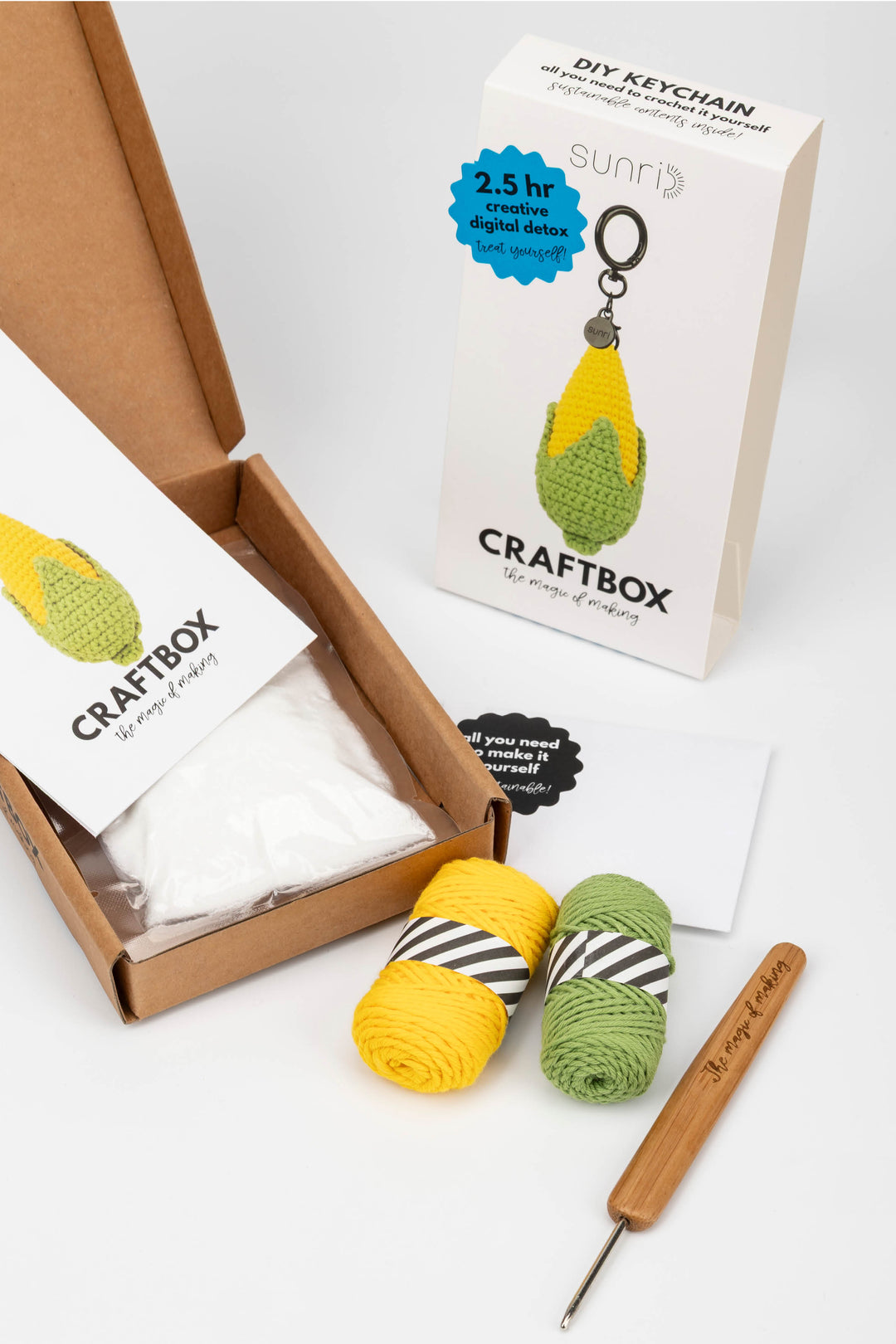 Craft kit with yarn, crochet hook, and keychain in a box on a white background