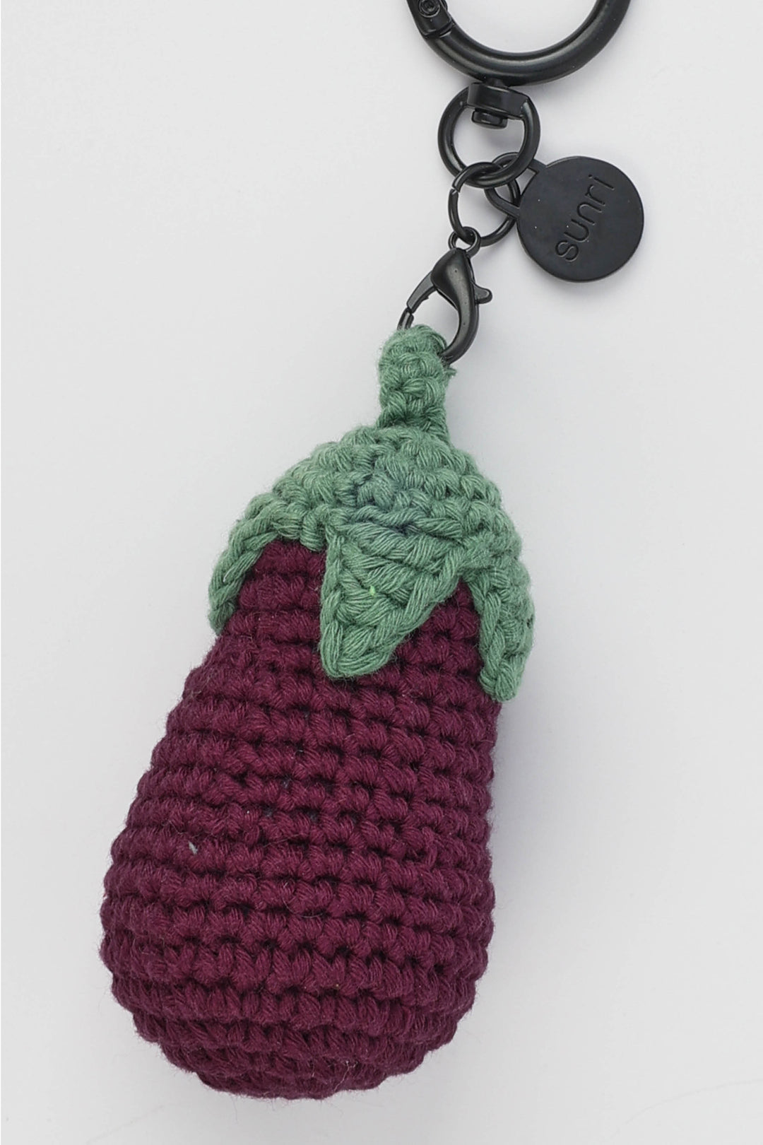 Crocheted eggplant keychain with a green stem on a white background