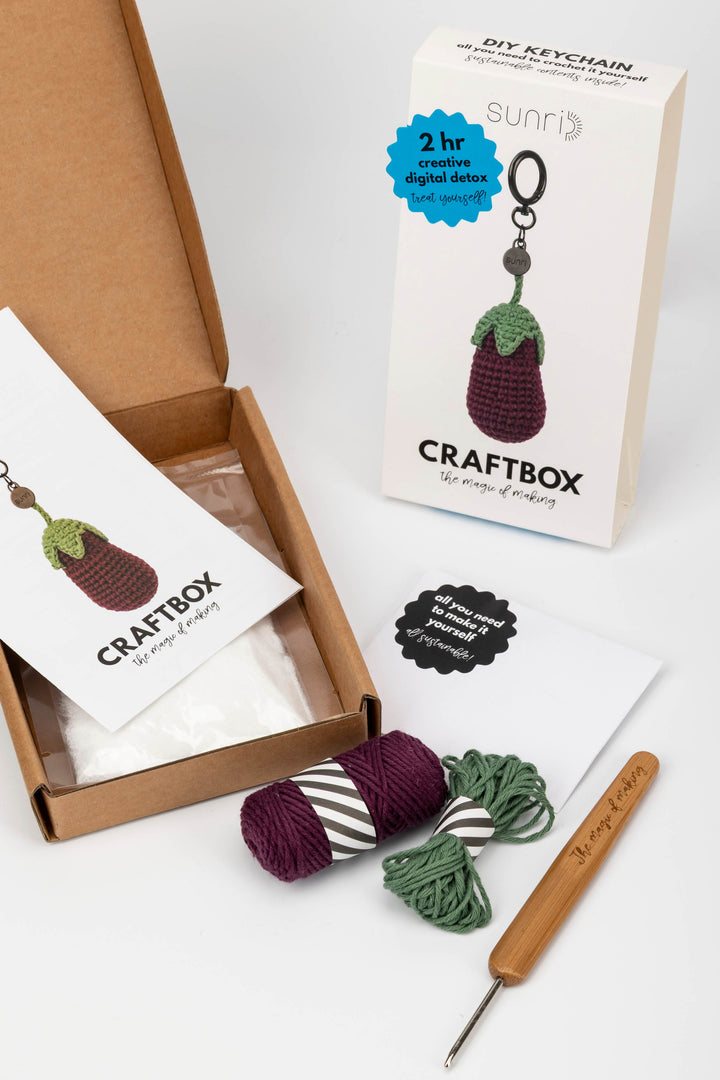 Craft box with yarn, crochet hook, and keychain kit on a white background