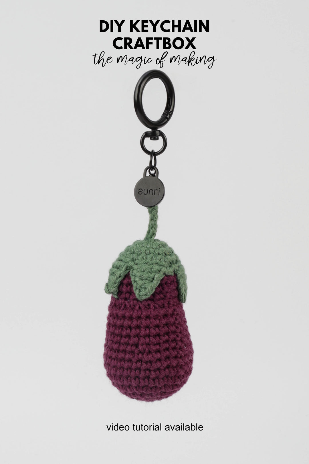 Crocheted keychain shaped like an eggplant on a white background with text about DIY keychain craftbox.