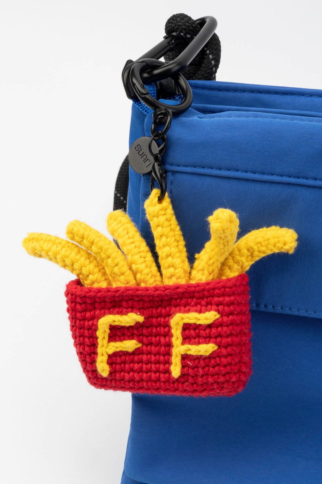 Crocheted French fry keychain attached to a blue bag