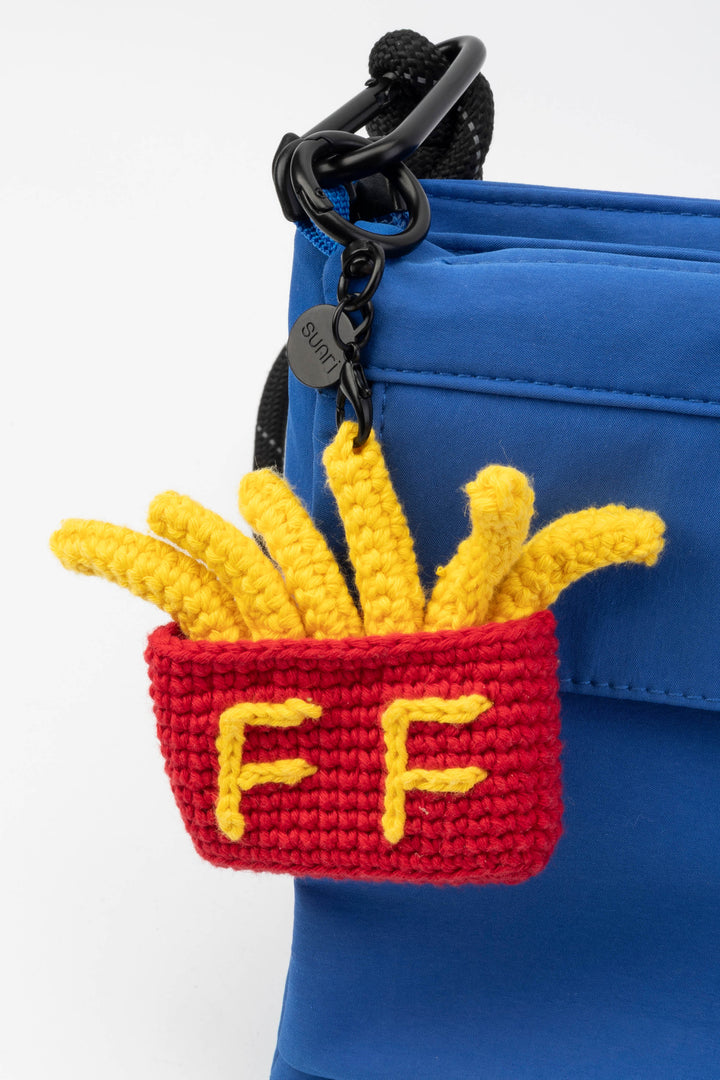 Crocheted French fry keychain attached to a blue bag