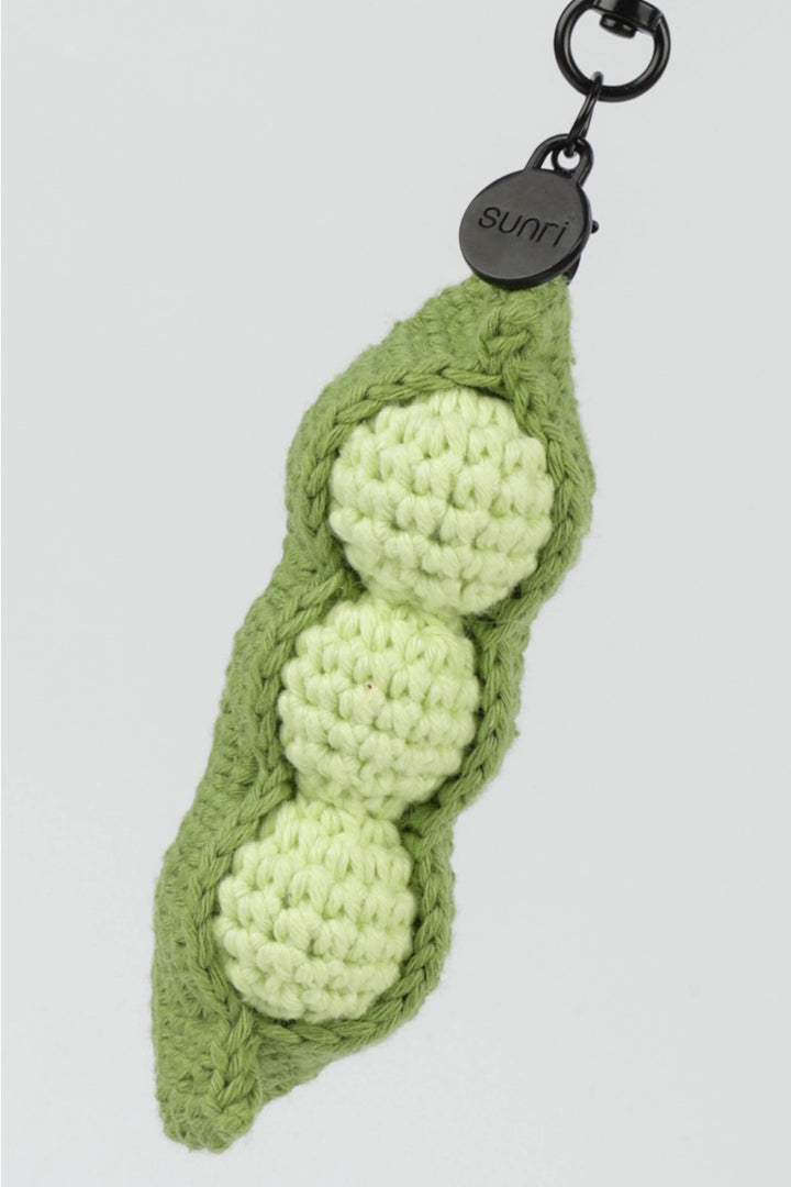 Crocheted green pea pod keychain with three peas on a light gray background