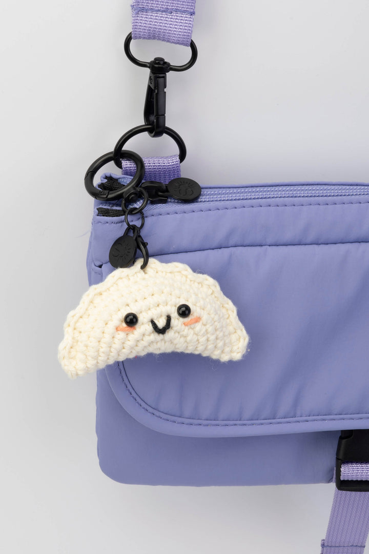 Gyoza-shaped keychain attached to a purple bag on a white background