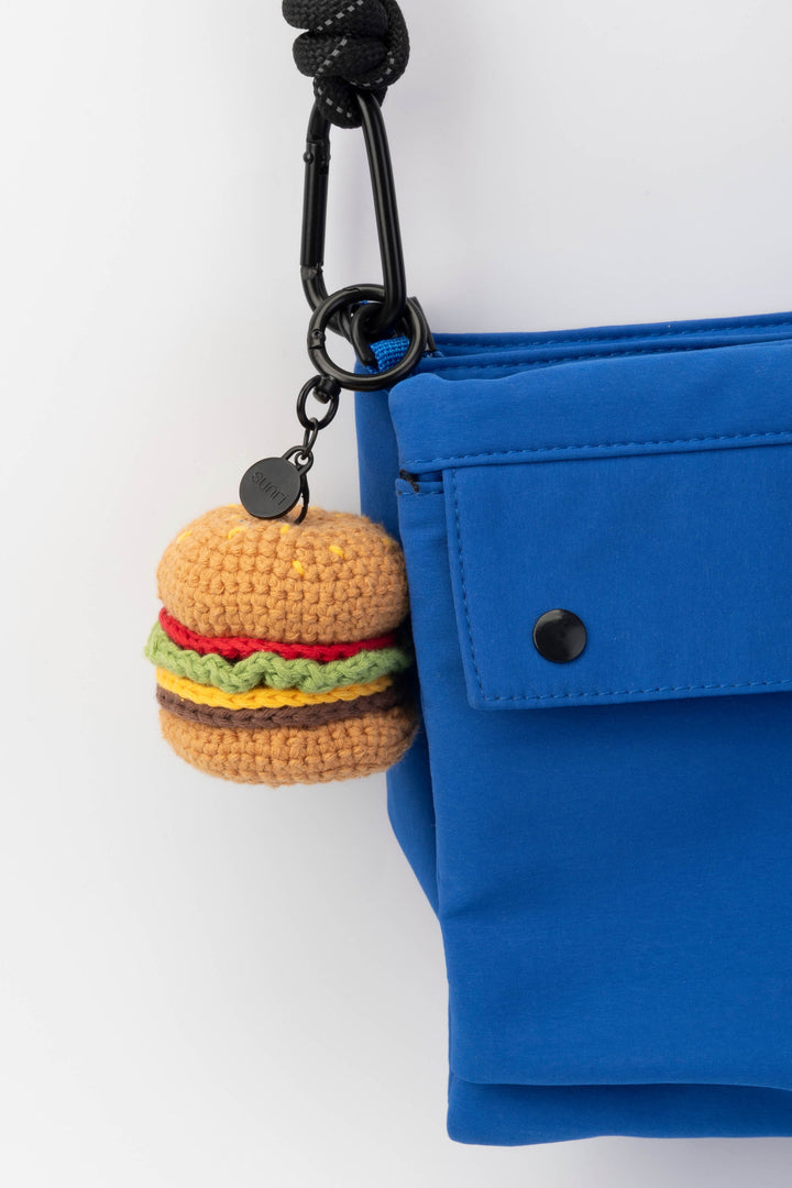 Blue bag with a keychain shaped like a hamburger on a white background