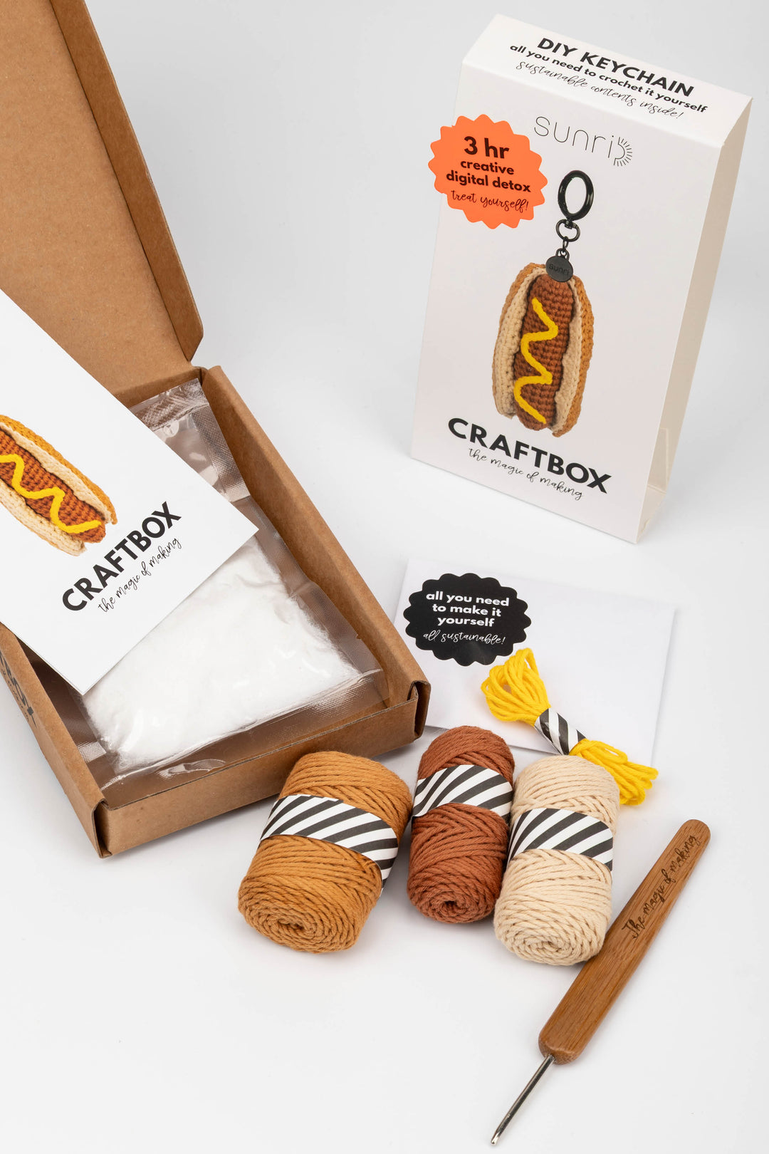 Craft kit with yarn, crochet hook, and packaging on a white background