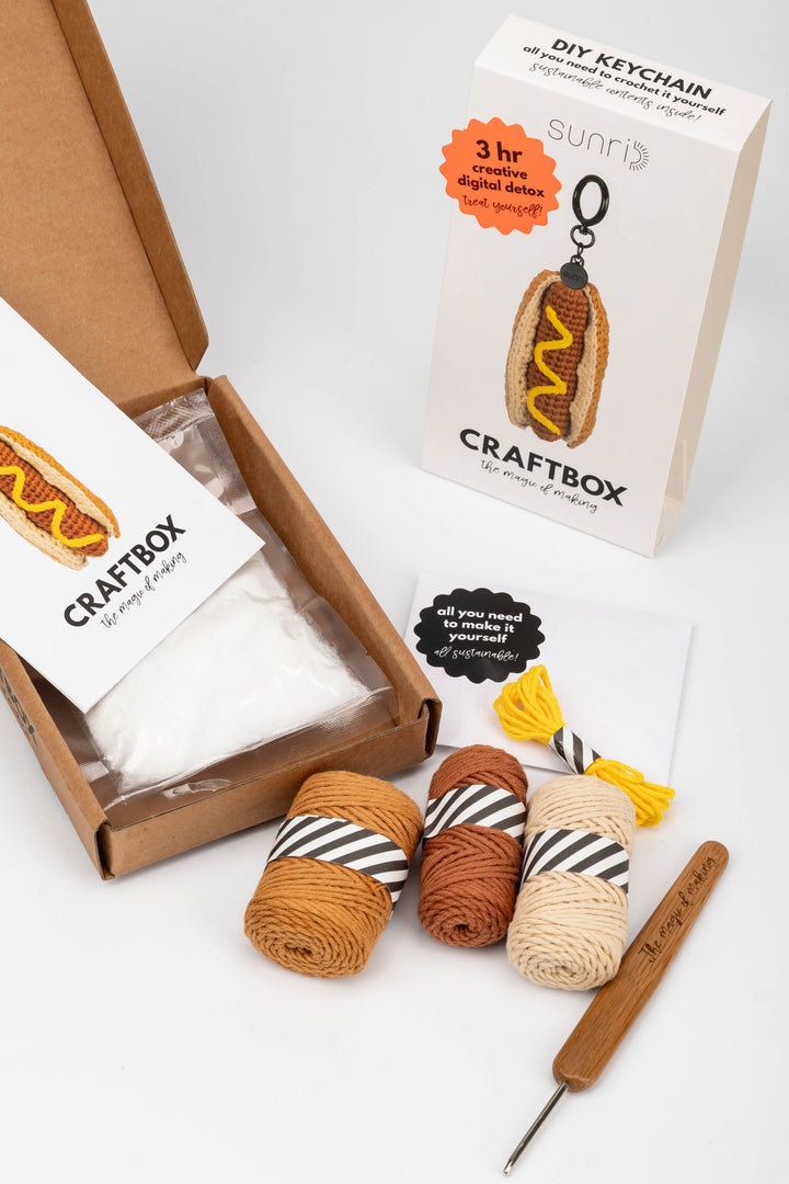 Craft kit with yarn, crochet hook, and packaging on a white background