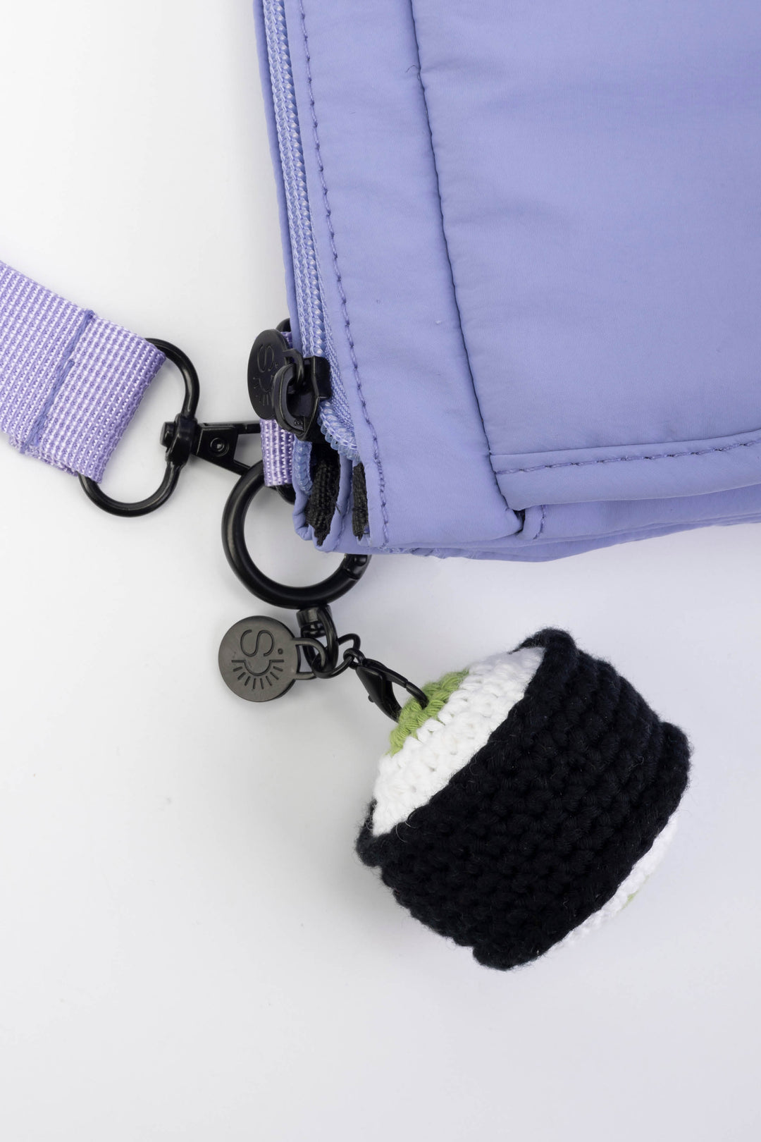 Black and white knitted keychain attached to a purple jacket on a white background