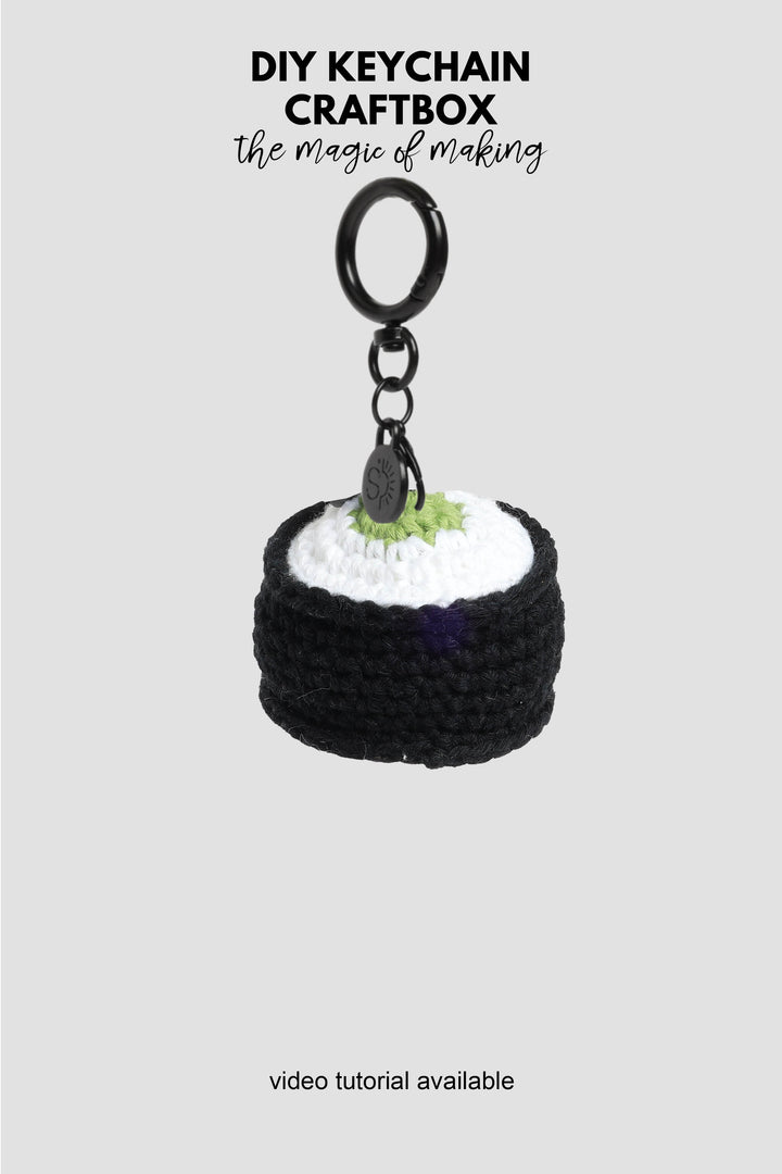 Crocheted sushi keychain with a black ring on a light gray background