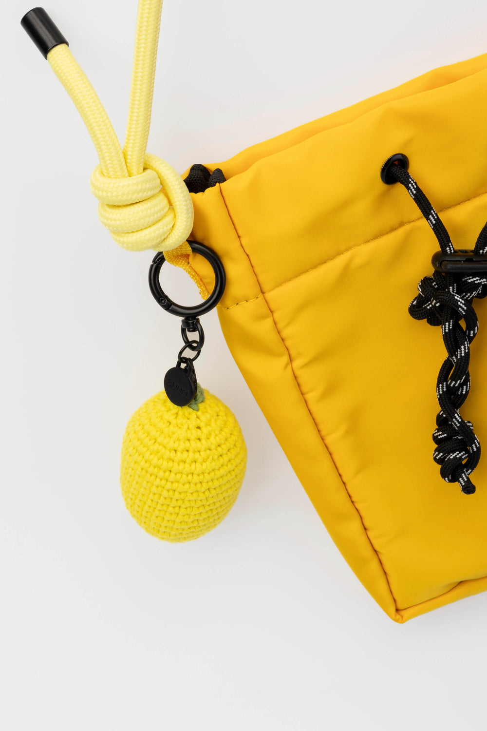 Yellow drawstring bag with a keychain featuring a yellow lemon and black rope on a white background