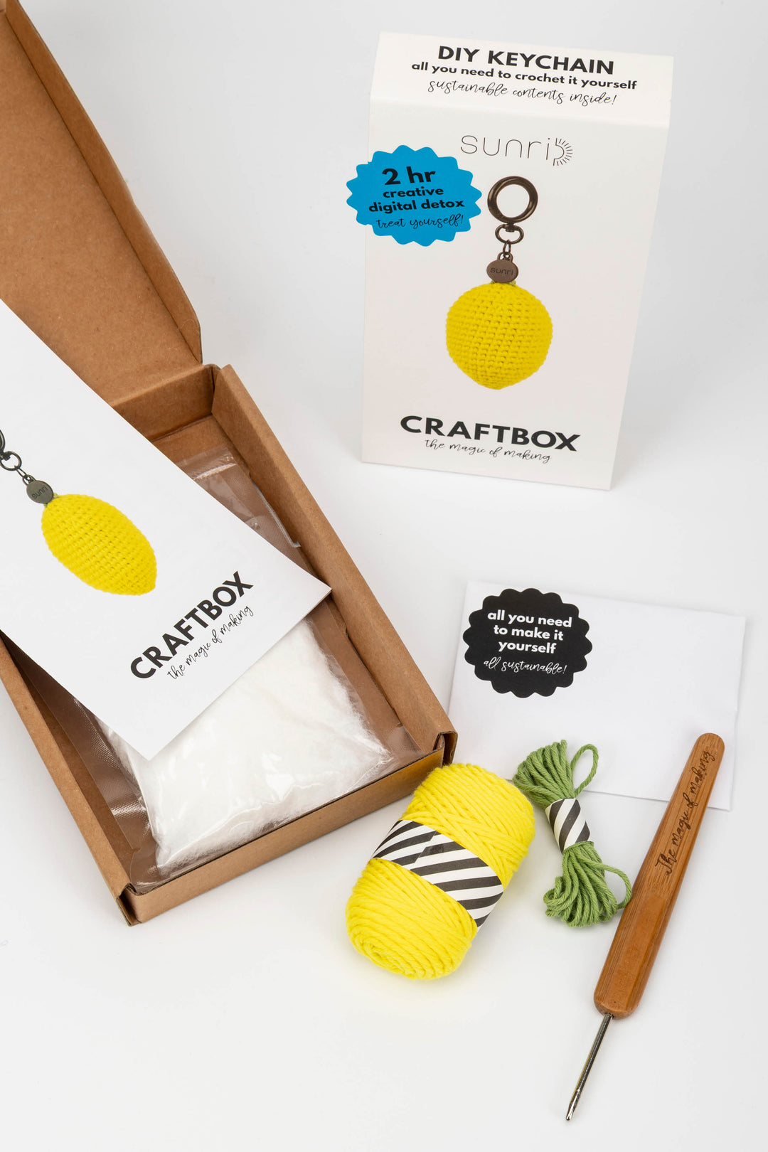 Craft kit with yarn, crochet hook, and packaging on a white background