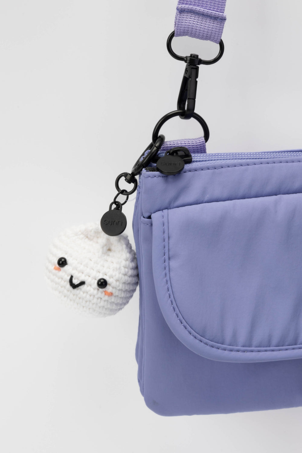 Purple bag with a cute white sushi charm on a light gray background