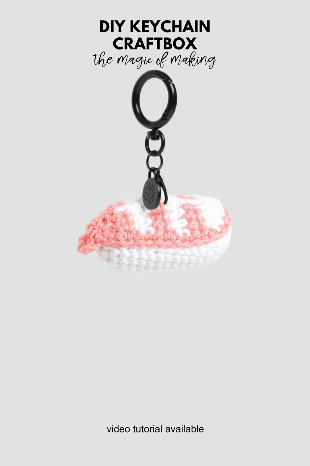 Crocheted keychain with pink and white design on a gray background, featuring text about DIY keychain craftbox.