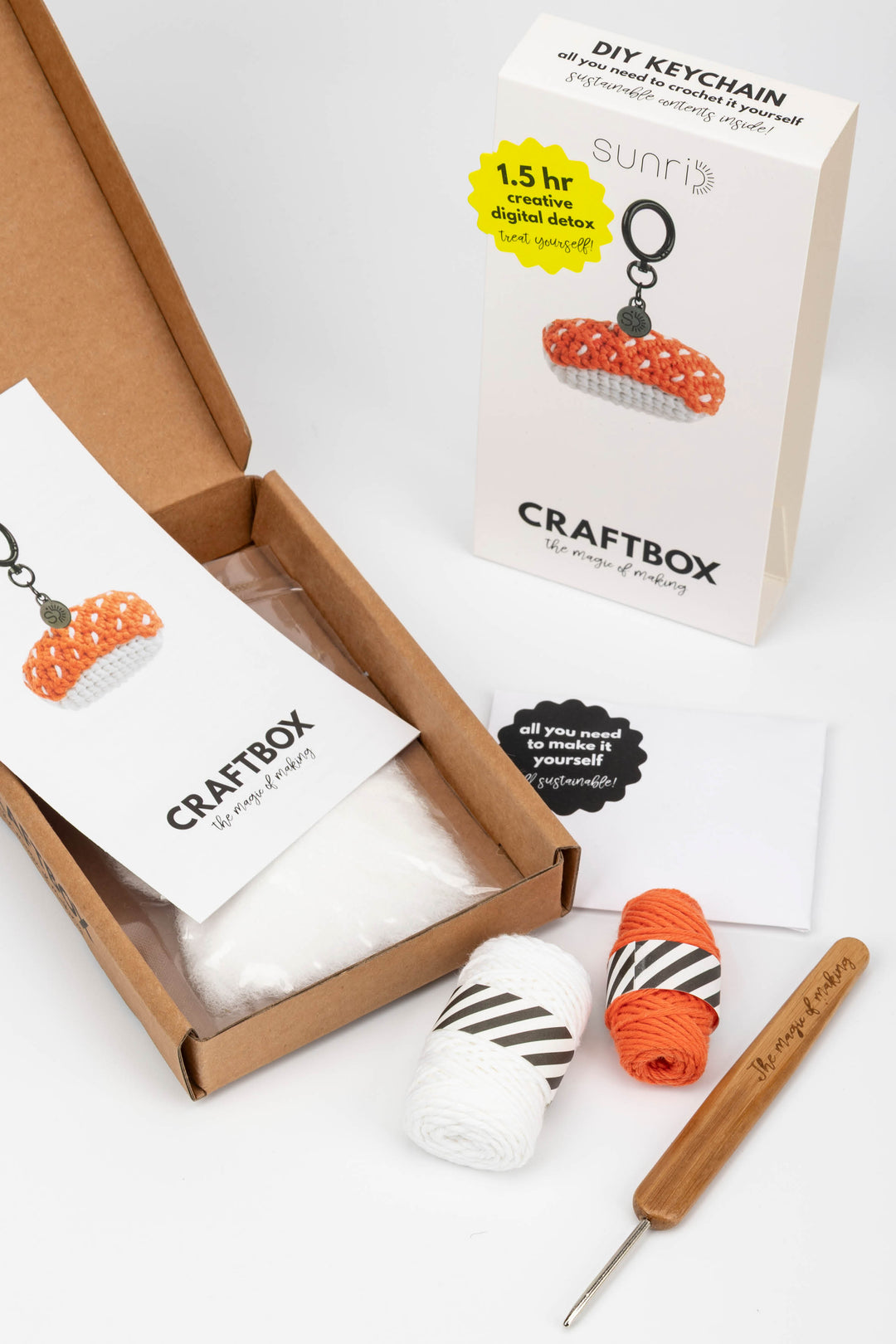 Craft kit with yarn, crochet hook, and packaging on a white background