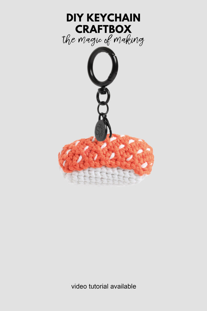 Crocheted sushi keychain with black ring on a white background, featuring text about DIY keychain craftbox.