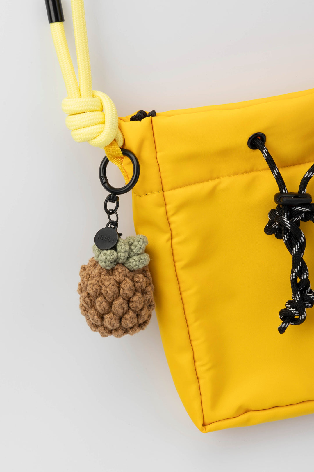 Yellow bag with a pineapple-shaped keychain on a white background