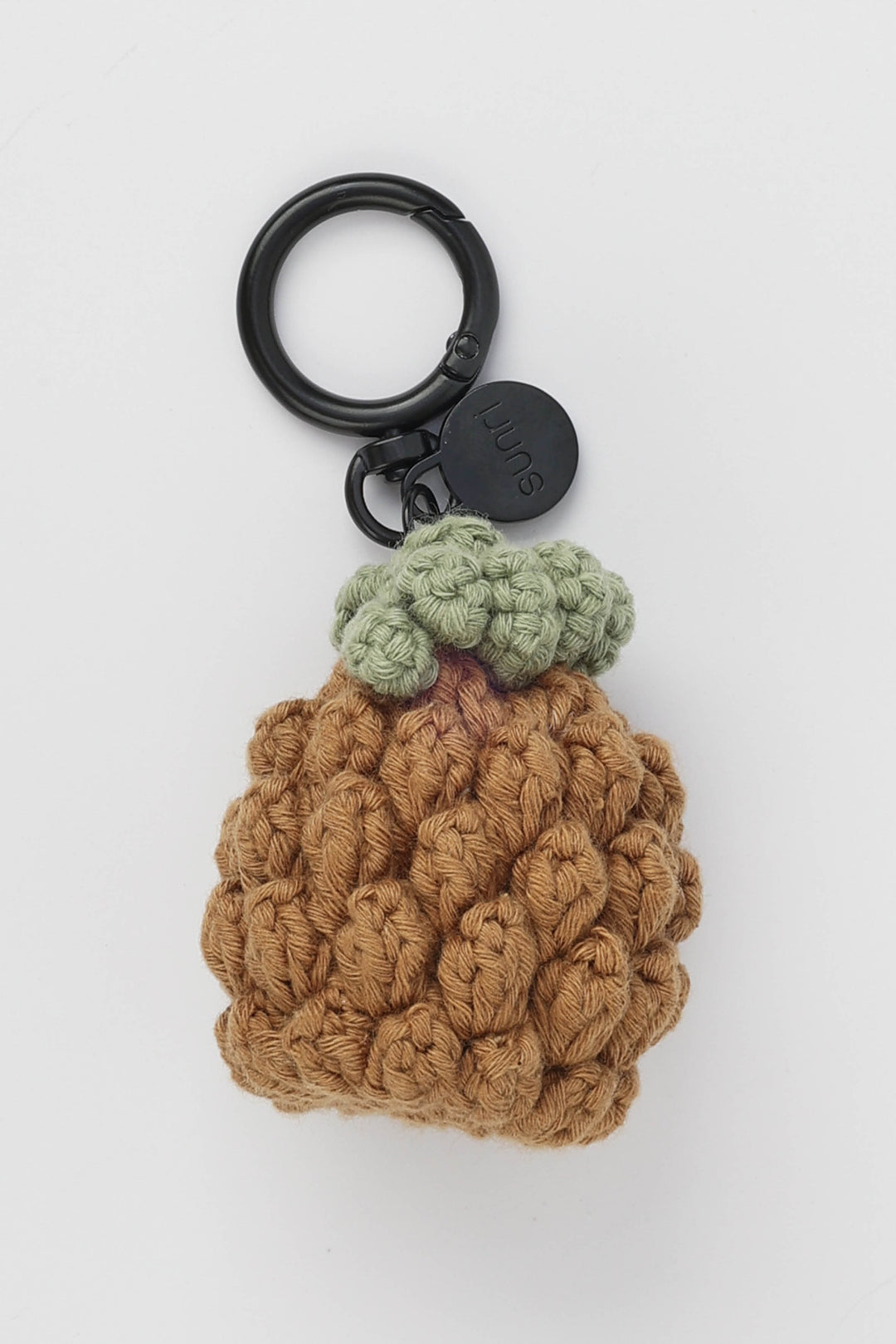 Crocheted pineapple keychain with a black ring on a white background