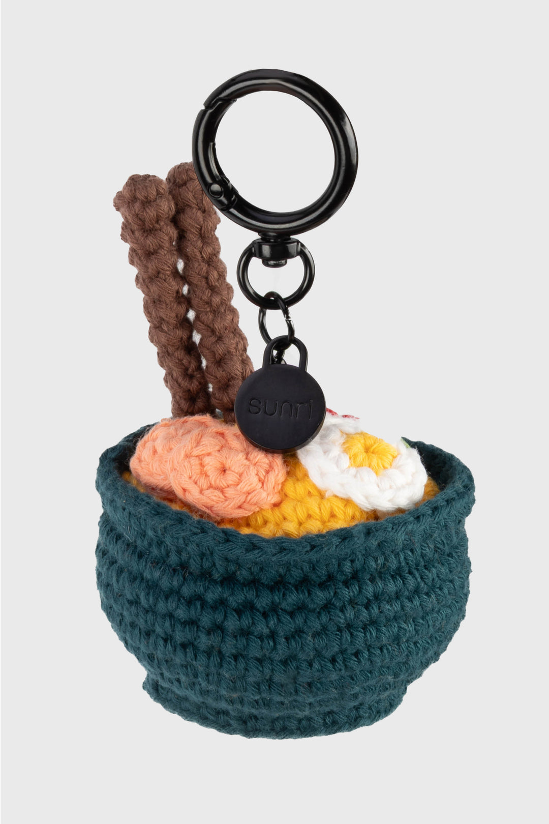 Crocheted ramen keychain with a black ring on a light gray background
