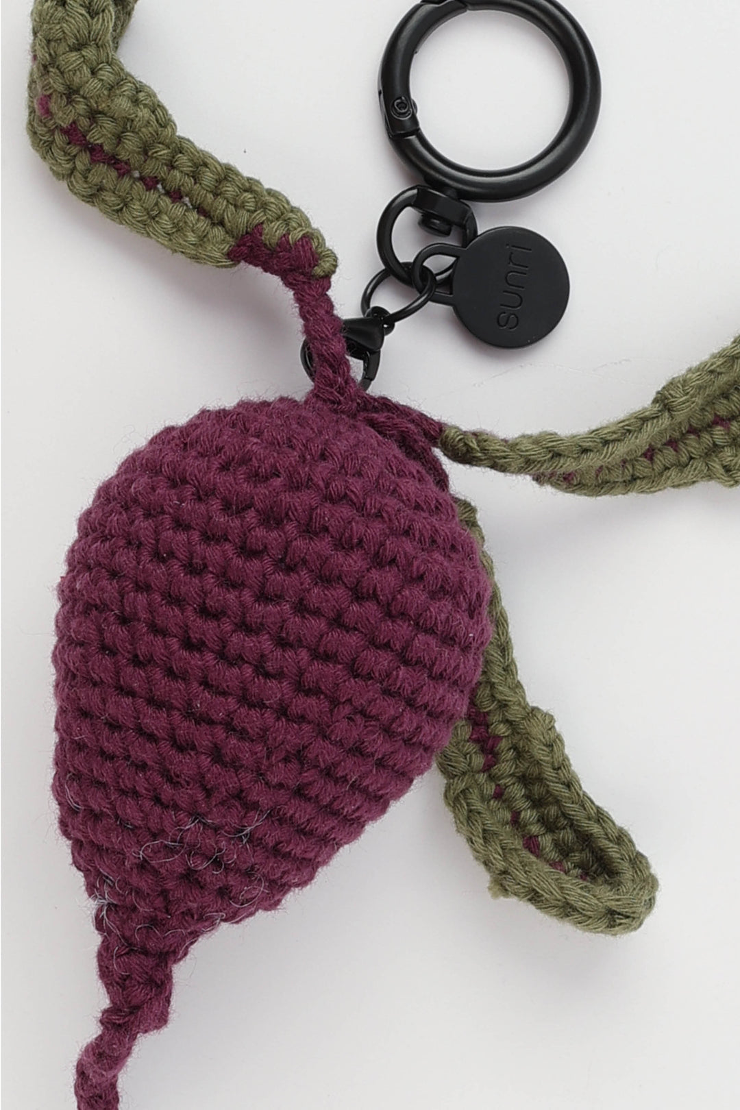 Crocheted keychain with a purple beetroot and green stem on a white background