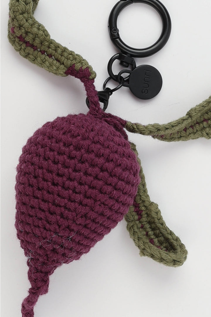 Crocheted keychain with a purple beetroot and green stem on a white background