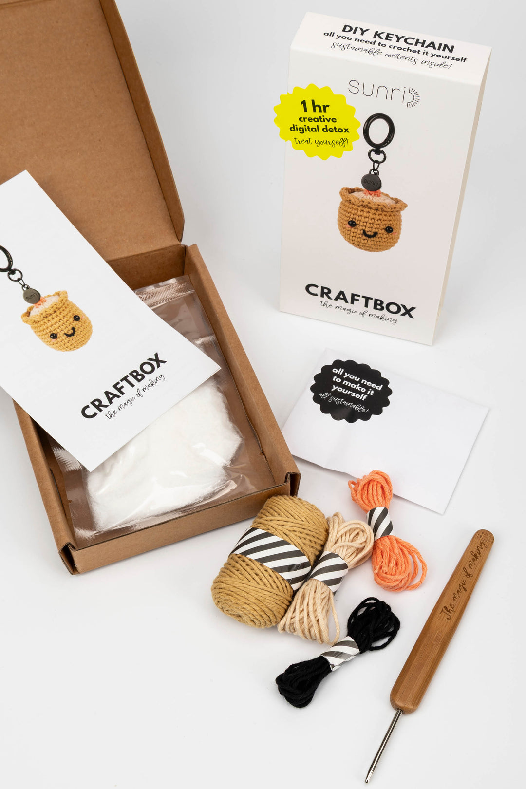 Craft kit with yarn, crochet hook, and keychain on a white background
