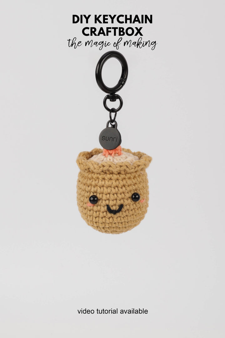 Crocheted sushi keychain with a smiling face on a white background, featuring 'DIY Keychain Craftbox' text.