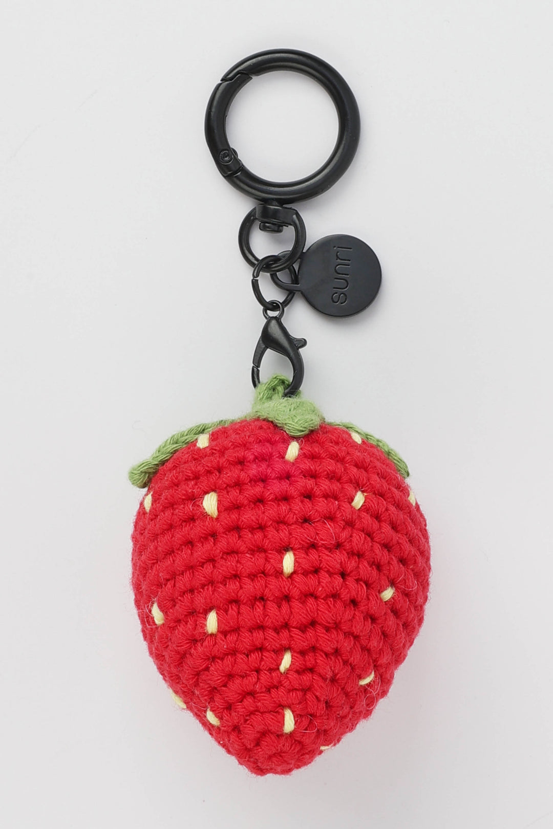 Crocheted strawberry keychain with a black metal ring on a white background