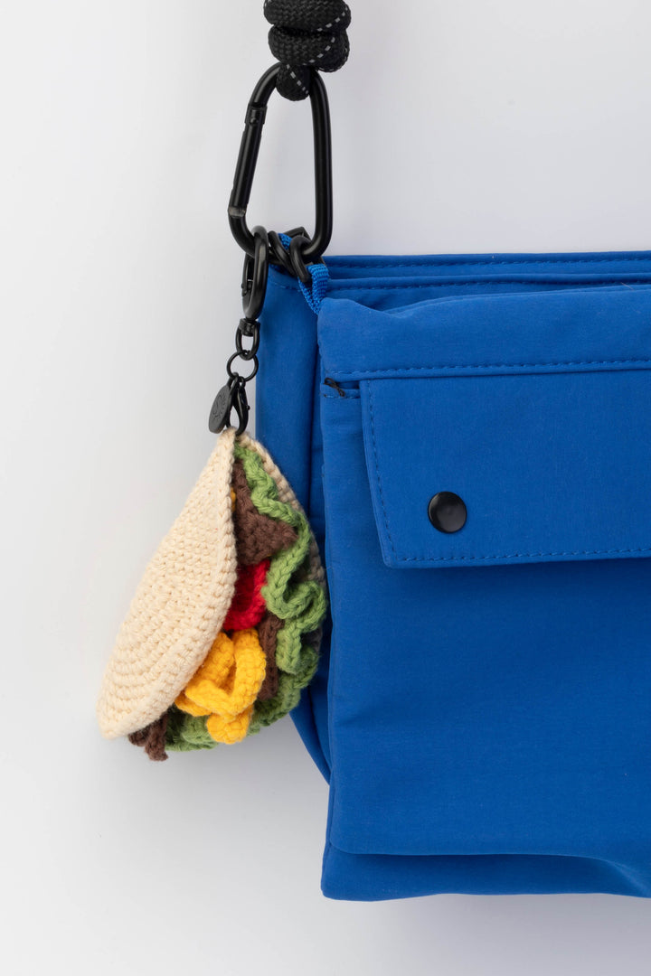 Blue bag with a colorful keychain attached on a white background