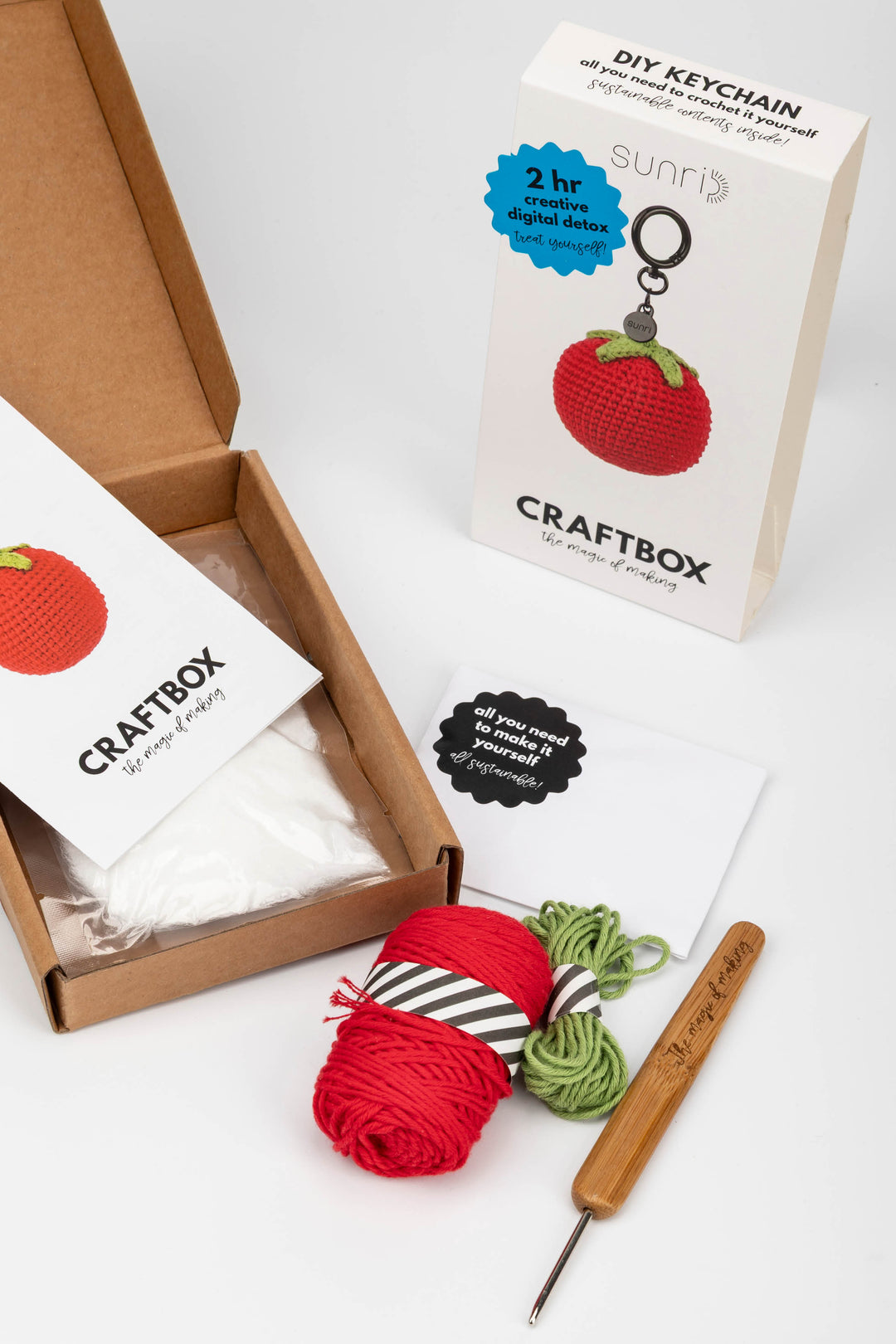Craft kit with yarn, crochet hook, and keychain on a white background