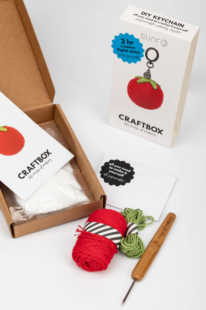 Craft kit with yarn, crochet hook, and keychain on a white background