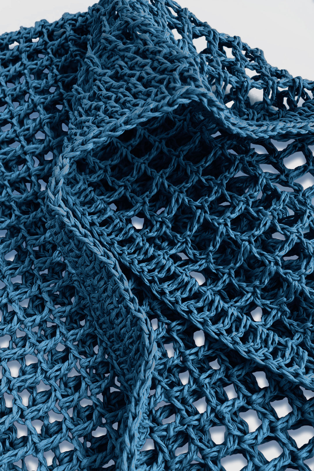 Close-up of a blue crocheted bag with a textured pattern.