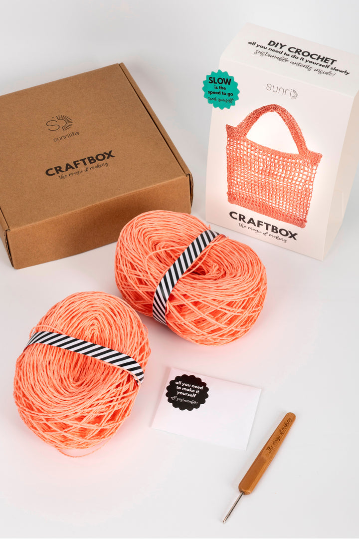 Craftbox with yarn and crochet hook on a white background