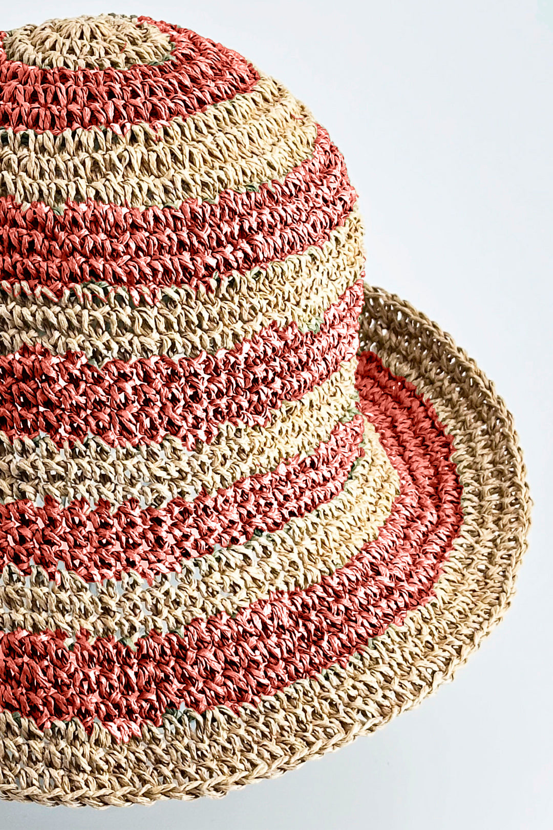 Straw hat with red and beige stripes on a light gray background