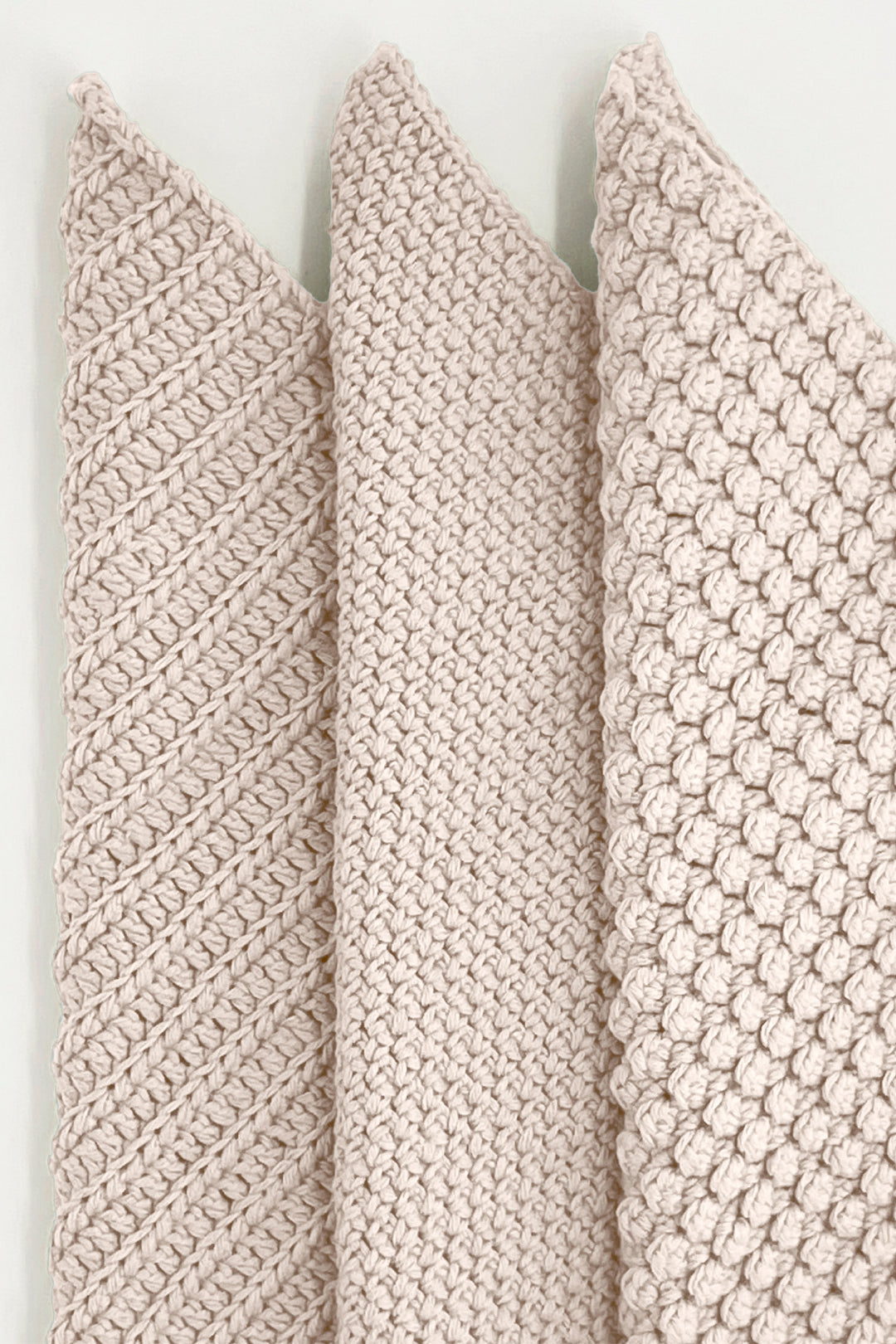 Three textured beige towels vertically on a light background