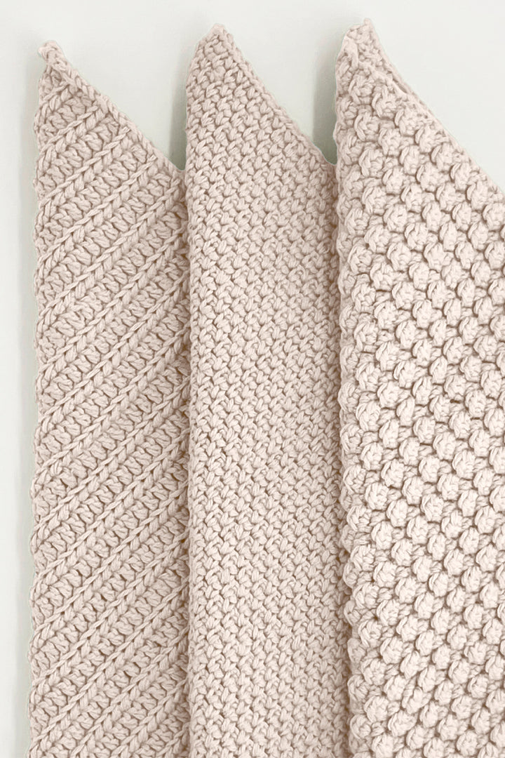Three textured beige towels vertically on a light background